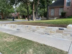New Lueders stone retaining wall along residential sidewalk replacing failed crosstie wall in North Richland Hills TX