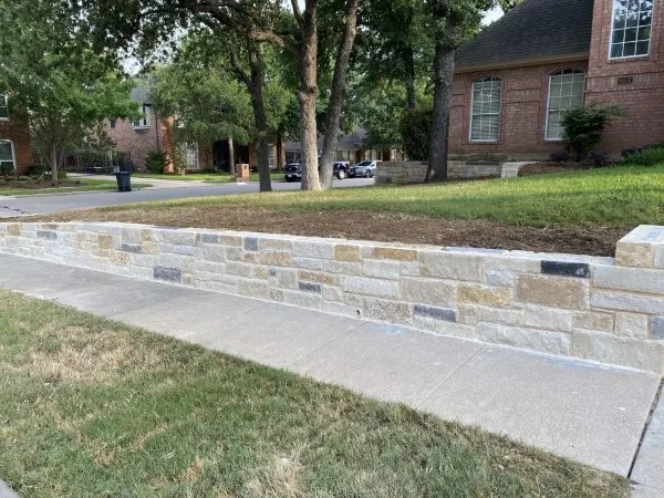 New Lueders stone retaining wall along residential sidewalk replacing failed crosstie wall in North Richland Hills TX