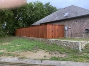 Milsap stone retaining wall replacing failed railroad cross ties beside brick home with cedar fence, Lake Dallas TX