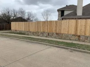 Milsap stone retaining wall base supporting a new cedar privacy fence along a residential street in Fort Worth TX