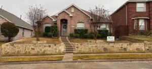 Milsap stone retaining wall with white mortar and center staircase fronting a brick home in Allen TX, replacing old cross-tie wall