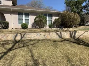 Milsap stone retaining wall replacing old cross-tie wall along front yard slope of brick home in Bedford, TX