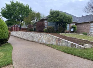 Curved Milsap stone retaining wall along residential driveway replacing old cross-tie wall, Bedford TX