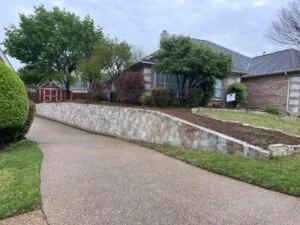 Newly built Milsap stone retaining wall along residential driveway in Bedford TX, replacing old wood cross-tie wall