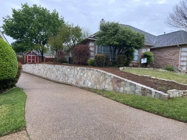 Newly built Milsap stone retaining wall along residential driveway in Bedford TX, replacing old wood cross-tie wall
