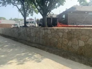 Newly built Milsap stone retaining wall along a residential driveway in Carrollton TX, replacing an old crosstie wall