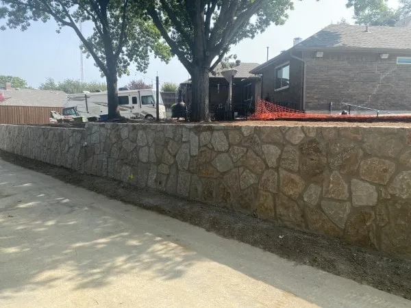 Newly built Milsap stone retaining wall along a residential driveway in Carrollton TX, replacing an old crosstie wall