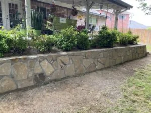 New Milsap stone retaining wall replacing a failing crosstie wall beside a backyard patio in Roanoke, TX