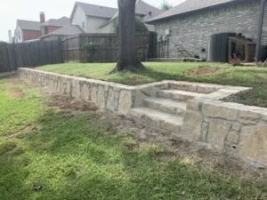 Milsap stone retaining wall with built-in steps terracing a backyard slope in Highland Village, TX