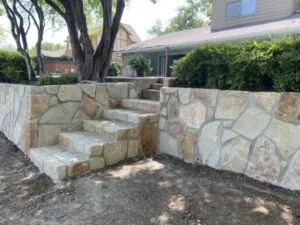 Milsap stone retaining wall with integrated stone steps replacing a failing crosstie wall at a Richardson TX home