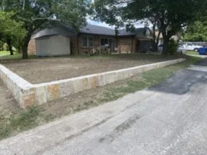 New Milsap stone retaining wall along front yard in Carrollton TX, replacing old wood wall, freshly graded soil behind it