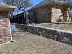 Completed natural stone retaining wall replacing old crosstie wall alongside brick home in The Colony TX