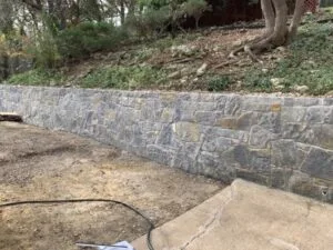 Silver Mist Hackett stone retaining wall replacing a failing wood wall on a sloped Fort Worth residential yard