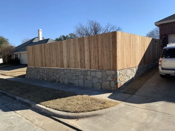 Stone retaining wall base supporting a new cedar privacy fence along a residential corner lot in North Richland Hills TX