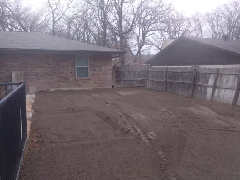 Backyard after vinyl-lined pool removal in Grapevine TX — level graded dirt ready for new use beside brick home and wood privacy fence