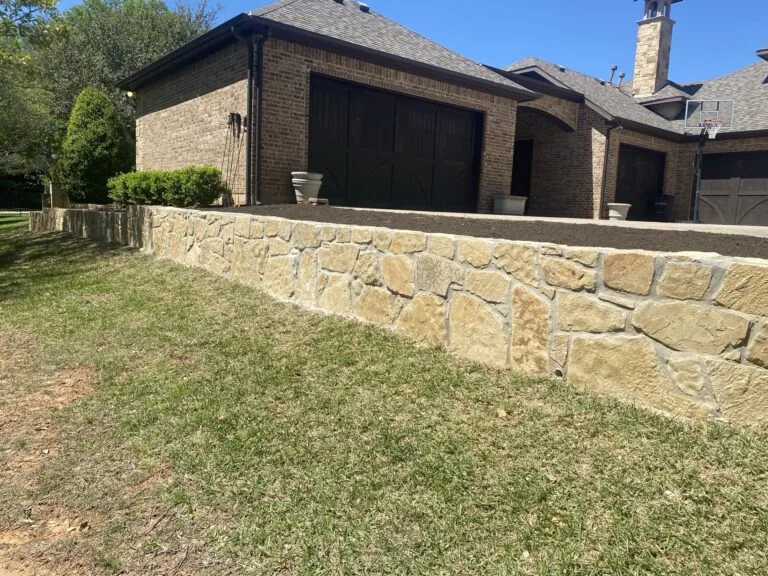 Milsap stone retaining wall leveling the sloped side yard beside a brick home garage in Colleyville TX
