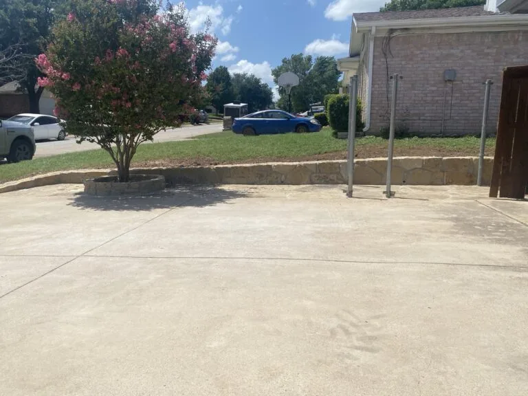 Low natural stone retaining wall along driveway edge holding raised front yard after crosstie wall replacement in Fort Worth TX