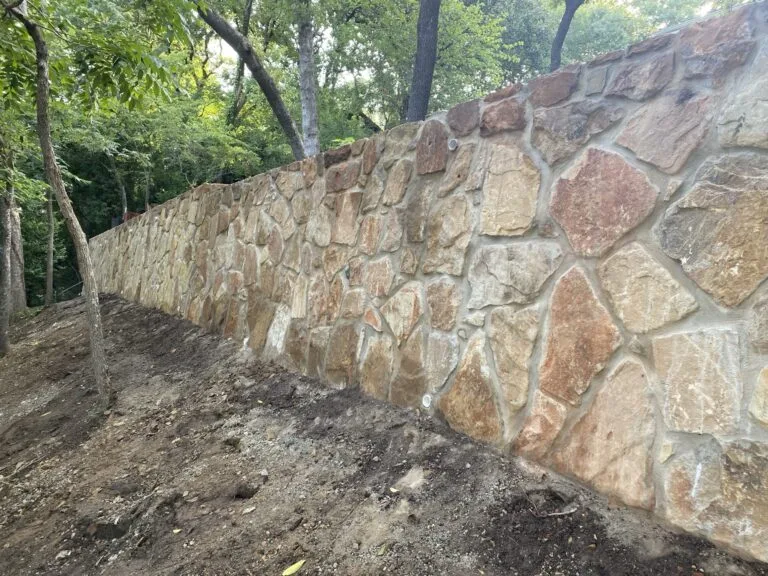 Newly built Milsap stone retaining wall replacing a failed crosstie wall on a wooded residential slope in Bedford, TX