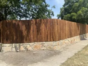 Natural stone retaining wall base supporting a cedar privacy fence along a sidewalk in Frisco TX