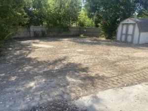 Backyard after partial pool removal in Fort Worth — level graded dirt lot with wood fence and storage shed, debris fully cleared