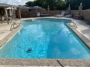 Full inground pool with pebble coping and brick surround wall at a Fort Worth home scheduled for residential pool removal