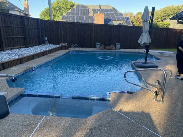 Full inground residential pool with concrete surround and wood privacy fence in Hurst TX, scheduled for partial pool removal