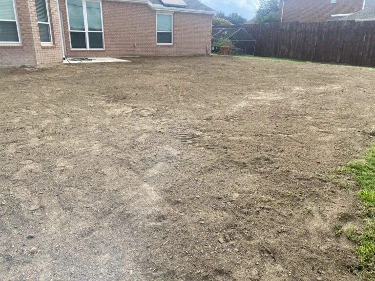 Backyard after pool removal in Plano TX — graded, compacted, and leveled dirt ready for new use next to brick home