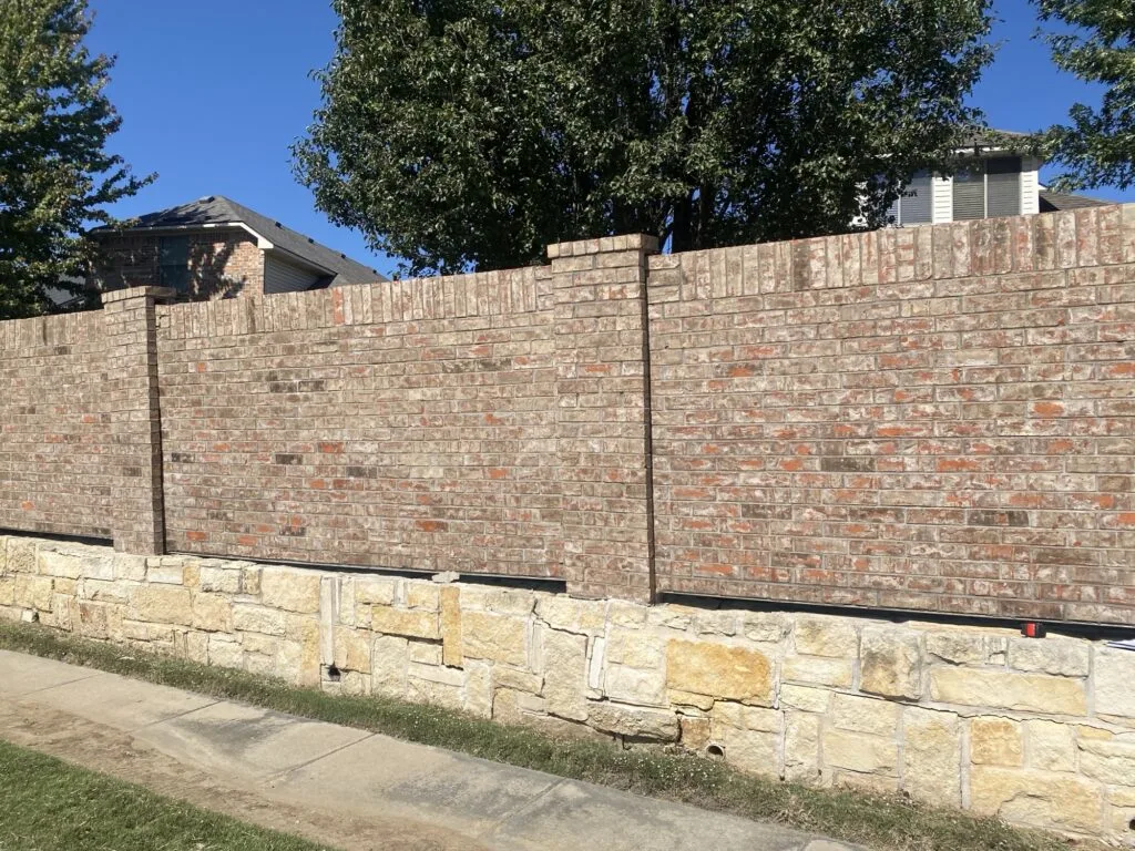 Granbury stone retaining wall base supporting a brick screen wall along a residential sidewalk in Fort Worth TX