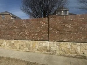Granbury stone retaining wall base supporting a replaced brick screen wall along a residential sidewalk in Fort Worth TX