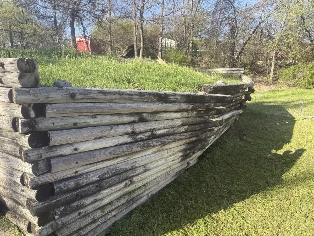 Weathered timber retaining wall in Azle, TX bowing under pressure from expansive clay soil before DFW rebuilt it