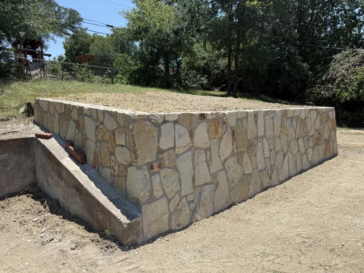 Corner of a finished stone retaining wall in Azle, TX showing the stepped return and drainage channel built by DFW Retaining Walls and Pool Demo