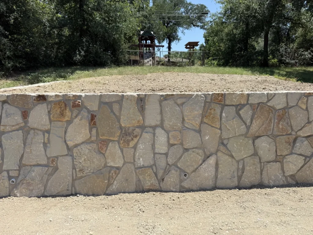 New engineered stone retaining wall in Azle, TX built by DFW Retaining Walls and Pool Demo with weep-hole drainage