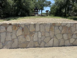 New engineered stone retaining wall in Azle, TX built by DFW Retaining Walls and Pool Demo with weep-hole drainage