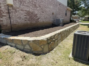 New Millsap stone retaining wall along a Flower Mound, TX home controlling the grade beside the foundation, built by DFW Retaining Walls and Pool Demo