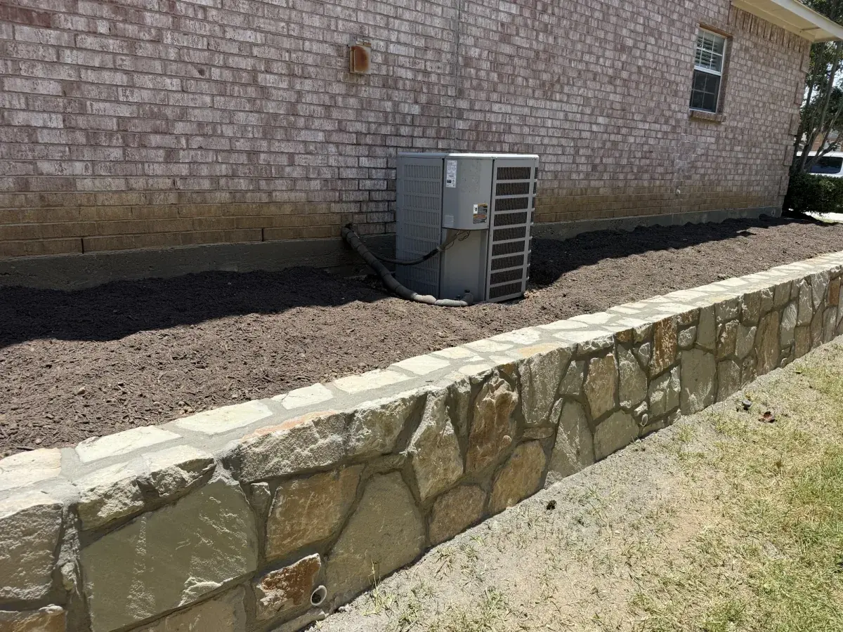 Stone retaining wall running along the side yard of a Flower Mound, TX home built by DFW Retaining Walls and Pool Demo