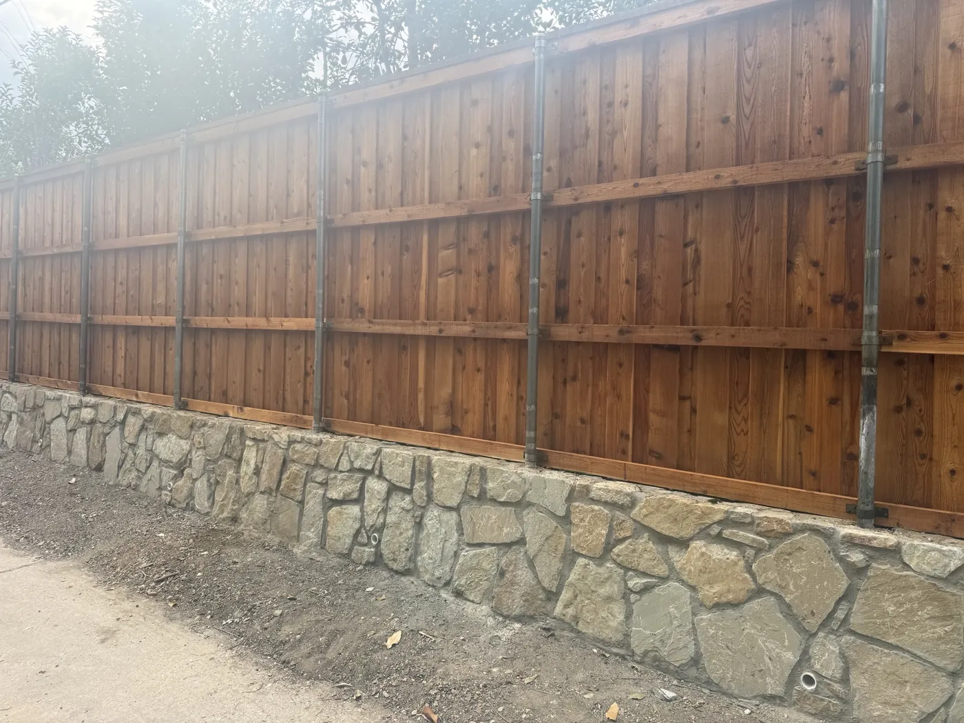 Stone retaining wall and 8' cedar fence — Dallas, TX New mortared stone retaining wall with weep holes and an 8-foot cedar fence along an alley in Dallas, TX