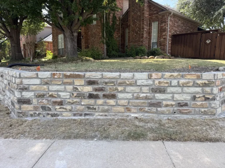 Rebuilt chopped-stone retaining wall with weep holes on a Plano, TX front yard, matched to the original stone